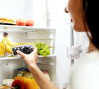 woman reaching for fruit in the fridge