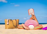 Woman in sun hat reading on a beach