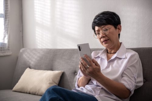 woman has questions while sitting alone texting on the mobile phone or shopping online. A retired woman on the sofa at home. And senior retired Concept