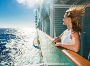 A woman smiling on the balcony of a cruise ship cabin
