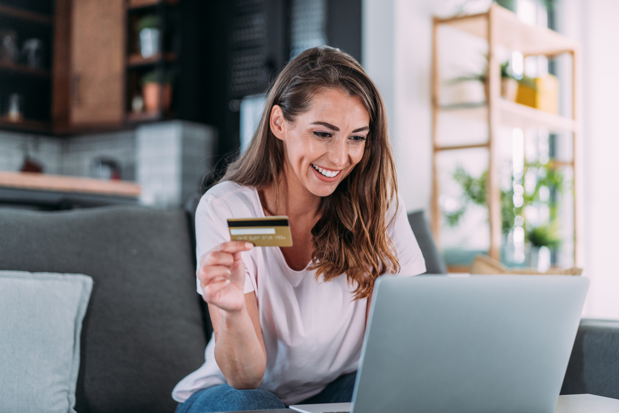 A woman shopping online with her laptop while holding her credit card