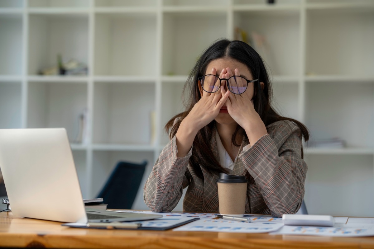 businesswoman stressed in front of her computer in an office with coffee