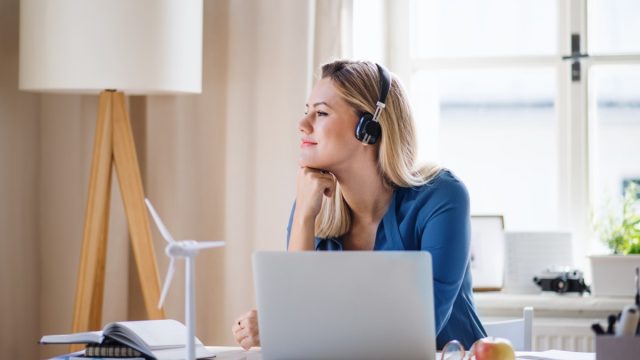 woman looking peaceful while she works at her desk with headphones on and a laptop in front of her