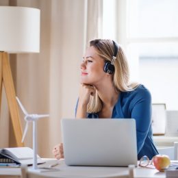 woman looking peaceful while she works at her desk with headphones on and a laptop in front of her