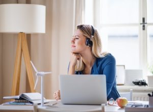 woman looking peaceful while she works at her desk with headphones on and a laptop in front of her