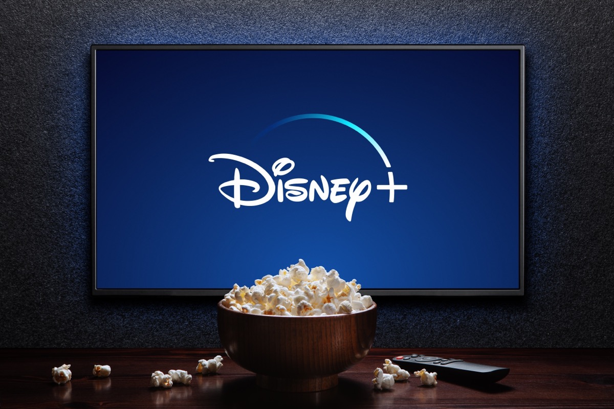 Disney plus logo on TV with popcorn bowl and reomote control on the table. Disney plus is an American subscription video streaming service. Astana, Kazakhstan - July 21, 2023.