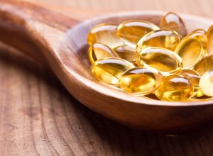 Cod liver oil omega 3 gel capsules isolated on wooden background