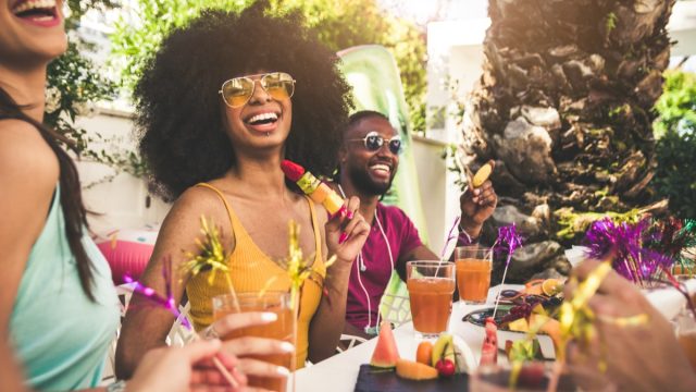 Group of friends eating and laughing at barbecue party