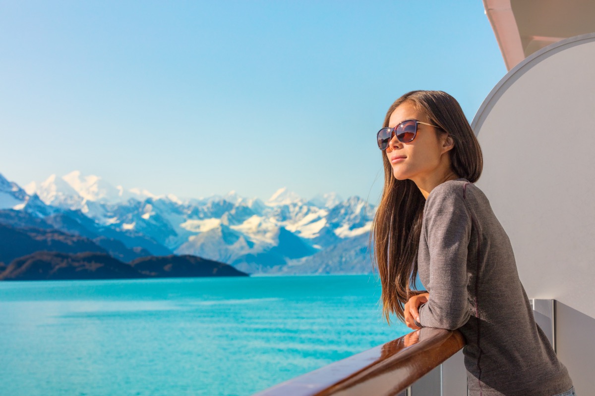 Luxury travel Alaska cruise holiday woman relaxing on balcony looking at view of mountains and nature landscape