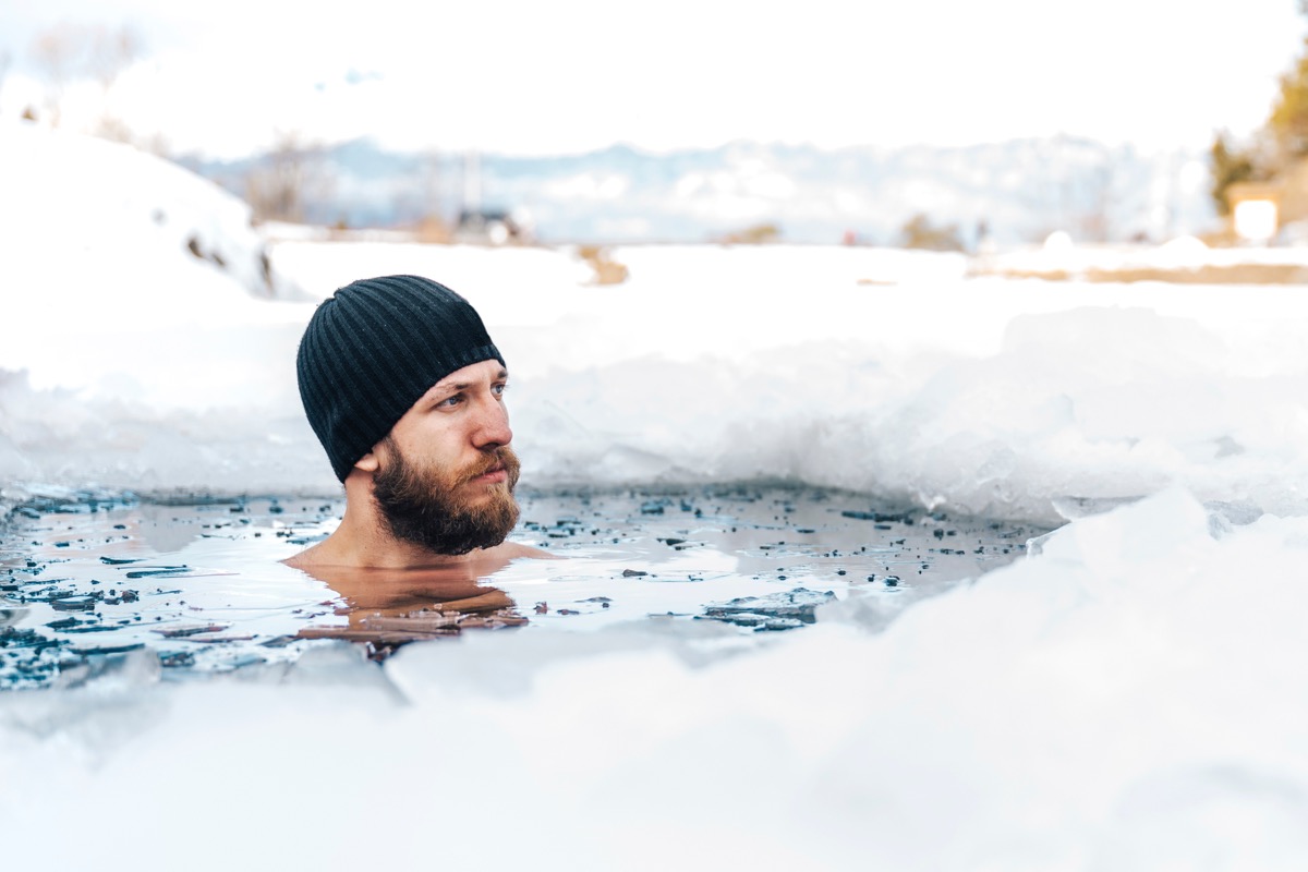 Young man with beard swims in the winter lake. 