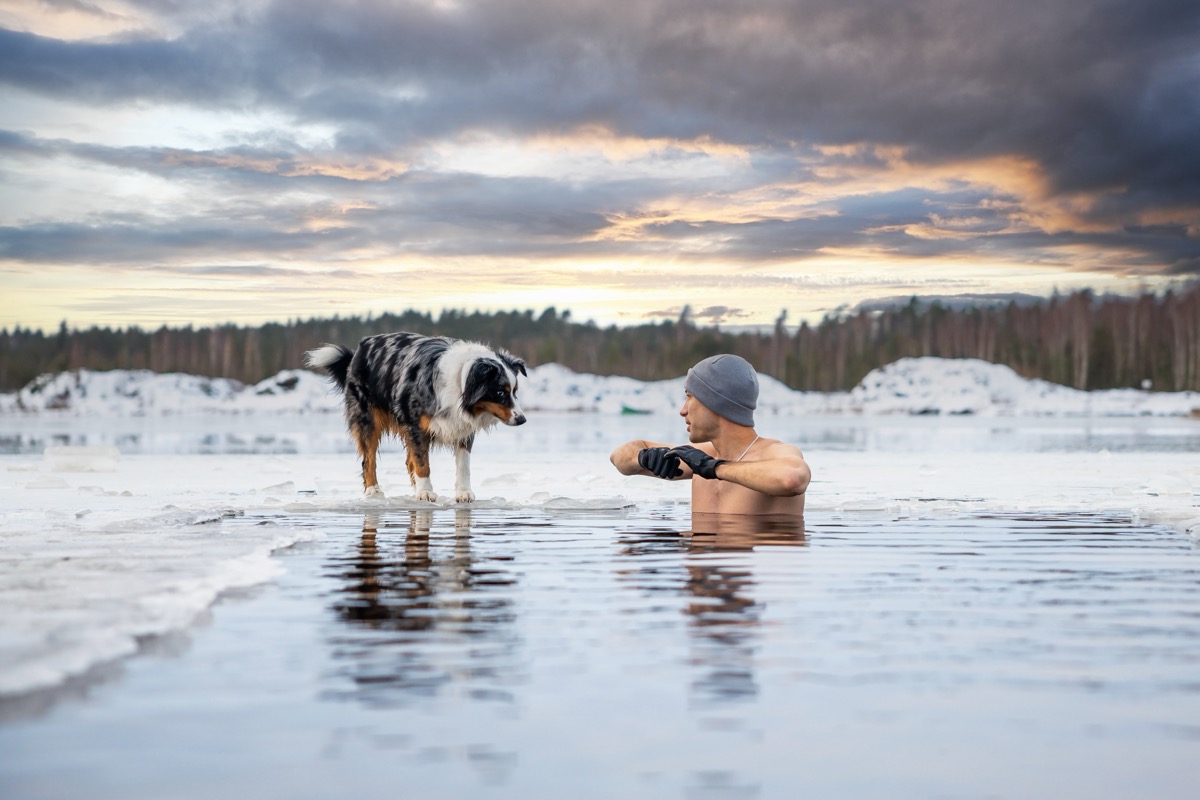 Strong man taking an ice bath with his dog