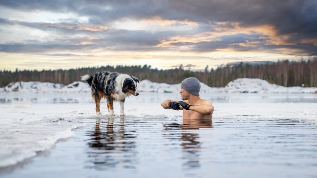 Strong man taking an ice bath with his dog