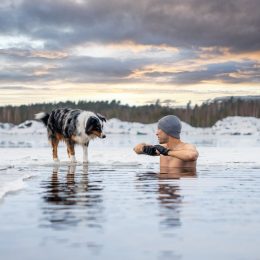 Strong man taking an ice bath with his dog