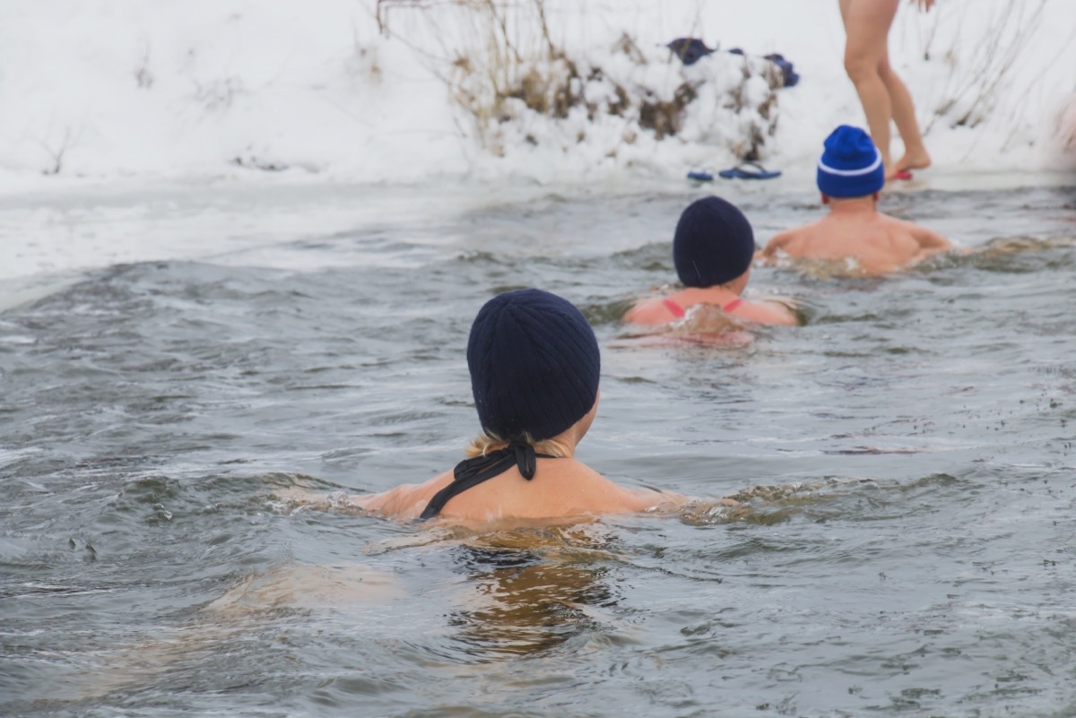 Man and woman swimming in winter cold water 