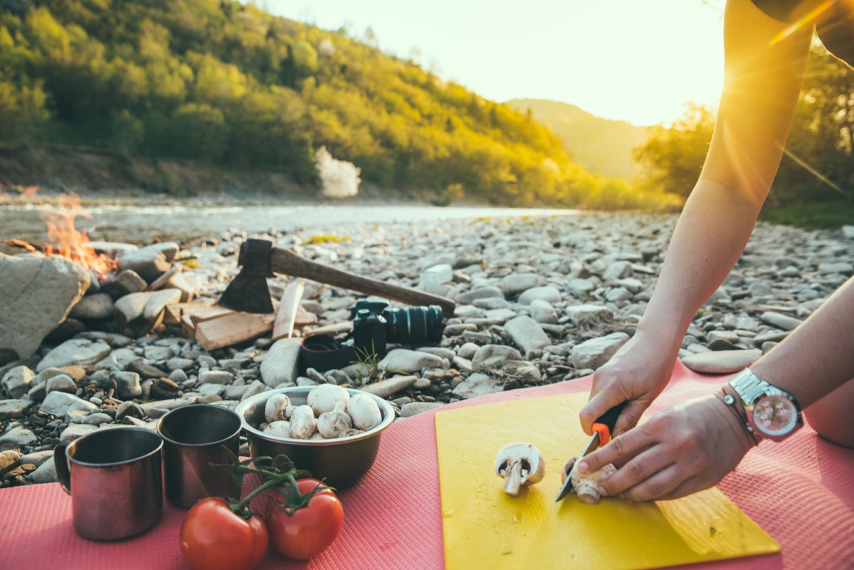 woman cooking on camp fire. wild nature resting. cutting mushrooms