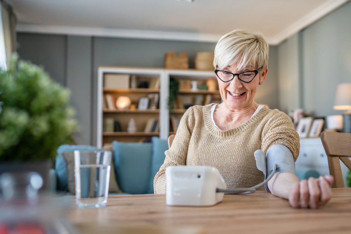 Happy senior woman checking her blood pressure levels at home