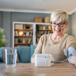 Happy senior woman checking her blood pressure levels at home