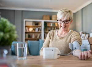 Happy senior woman checking her blood pressure levels at home