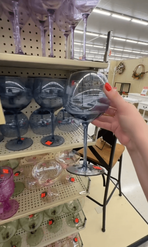 Shopper holding up tinted blue wine glass at Hobby Lobby