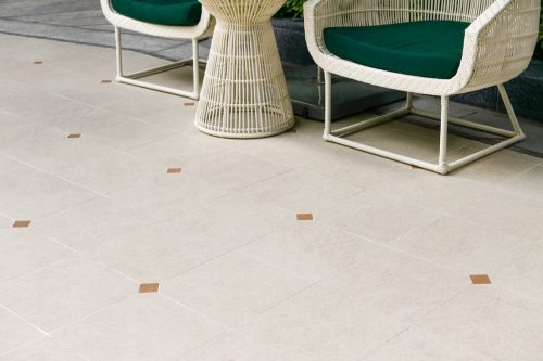 Outdoor terrace area with beige ceramic floor tile with sitting area. 
