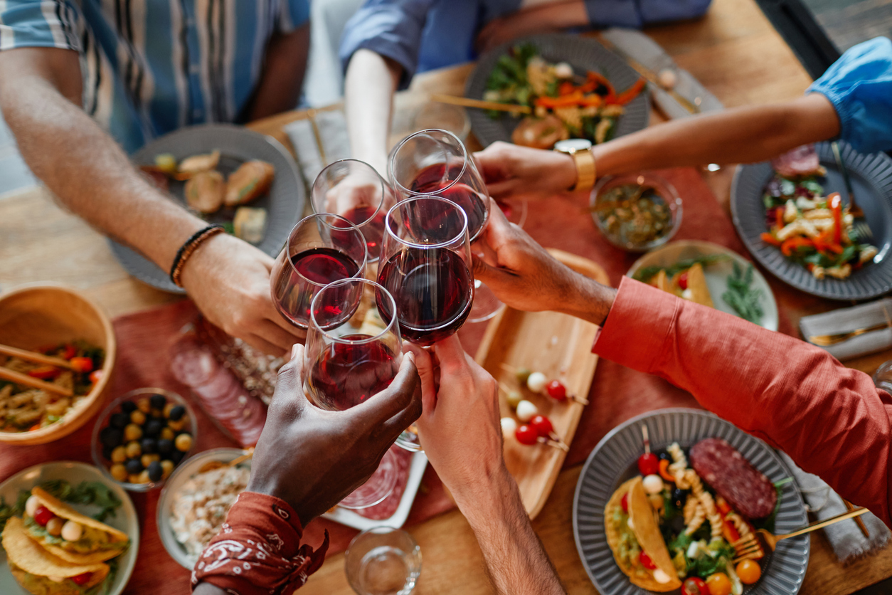 A close up of friends cheersing glases over a dinner table