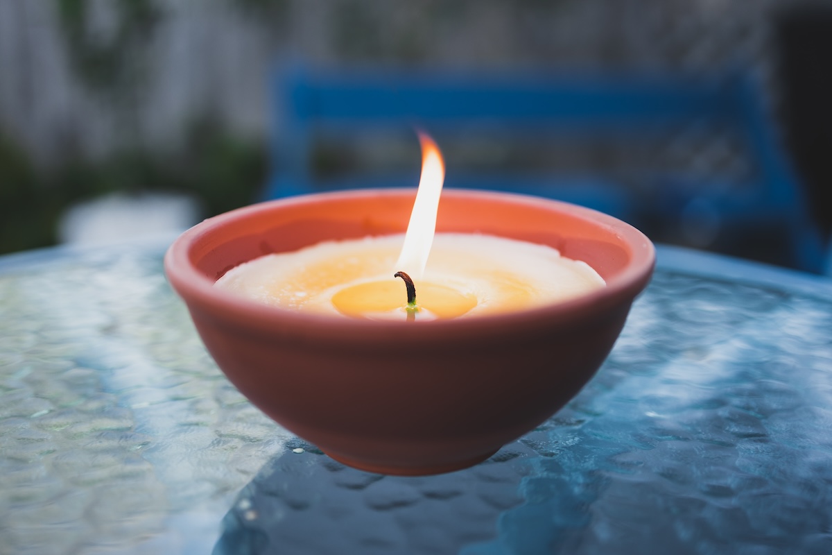 citronella candle with flame outdoor on cafe table setting at dusk