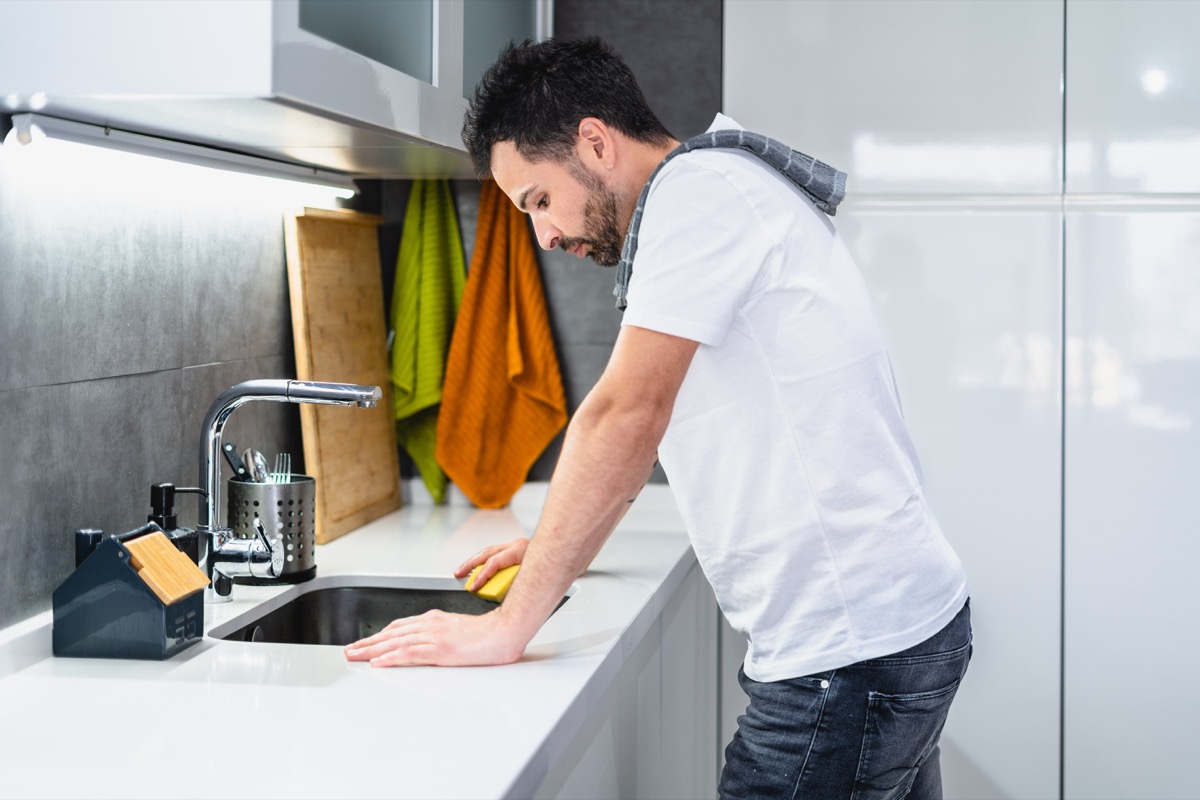 young man performing household chores in the kitchen, lifestyle concept