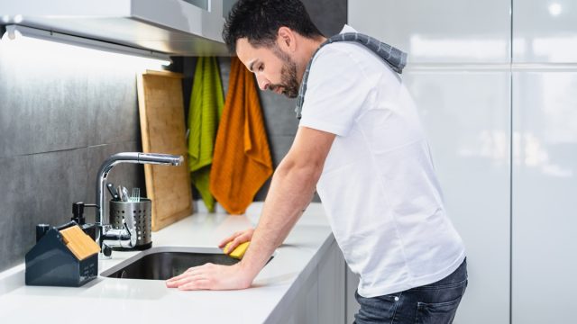young man performing household chores in the kitchen, lifestyle concept
