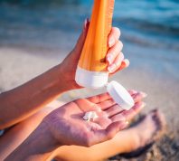 Woman using sunscreen cream on the beach