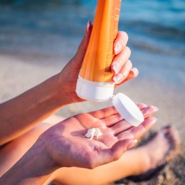 Woman using sunscreen cream on the beach