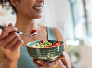Close up of athletic woman eating a healthy fruit bowl in the kitchen at home
