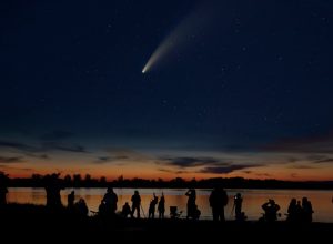 Comet Neowise and crowd of people silhouetted by the Ottawa river watching and photographing the comet