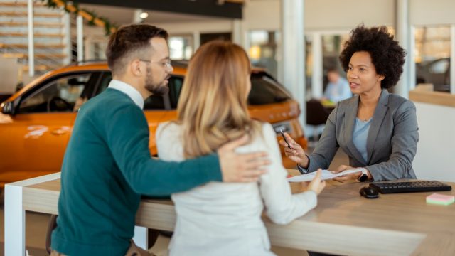 couple at car dealership talking to saleswoman