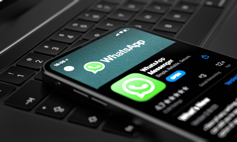 A close up of a phone sitting on top of a keyboard downloading the WhatsApp app