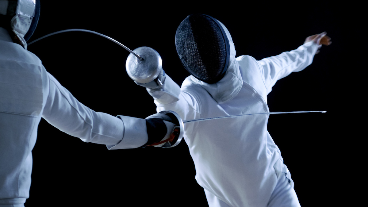 Two Professional Fencers Show Masterful Swordsmanship in their Foil Fight. They Attack, Defend, Leap and Thrust and Lunge. Shot Isolated on Black Background.