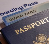 A close up of a passport with a Global Entry card in it sitting on a boarding pass