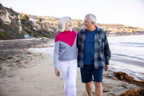 happy older couple walking on the beach