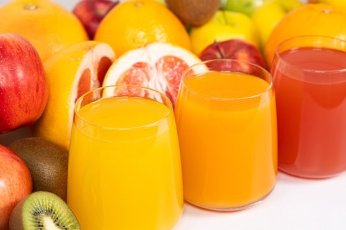 Different fruit juices in glasses on white background.
