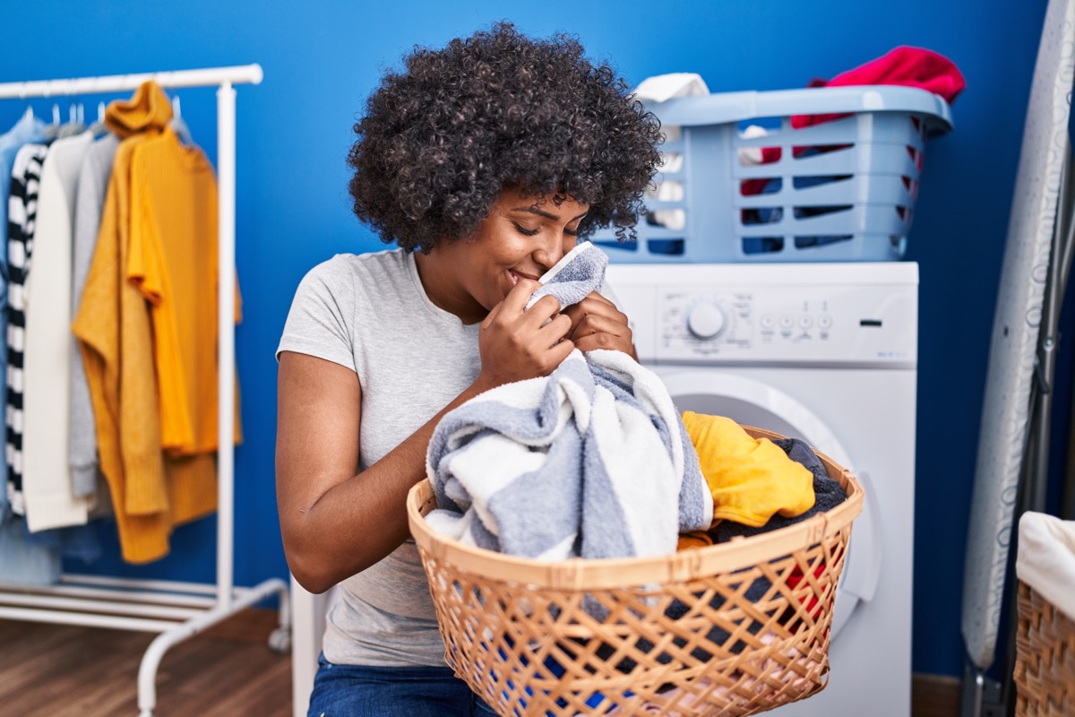 woman smelling towel standing at laundry room