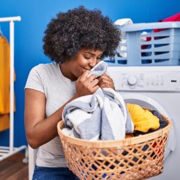 woman smelling towel standing at laundry room