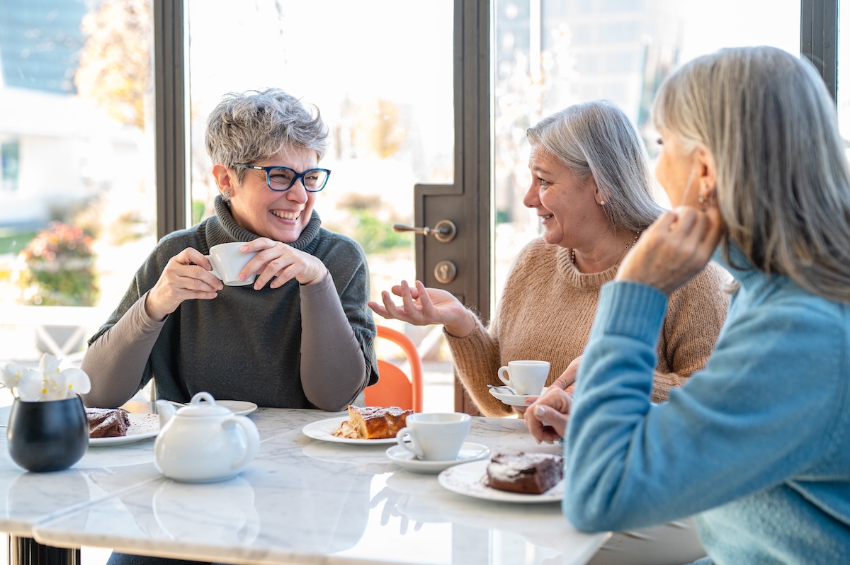 Group of mature women having fun during breakfast while drinking coffee and eating cake