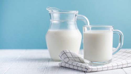 Banner of a glass of milk, a jug of milk on blue background. The concept of farm dairy products, milk day. Copy space.