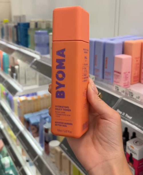 Shopper holding up a bottle of Byoma cleanser at Target