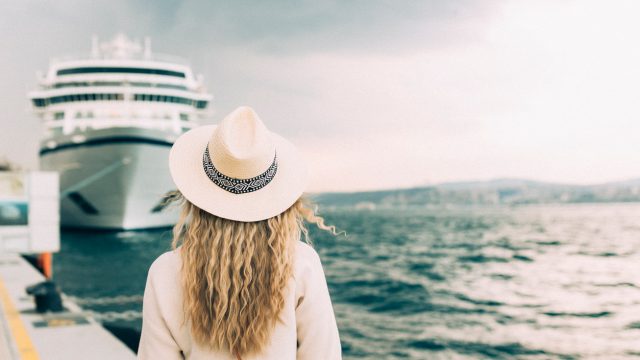 A woman standing near a cruise ship in port