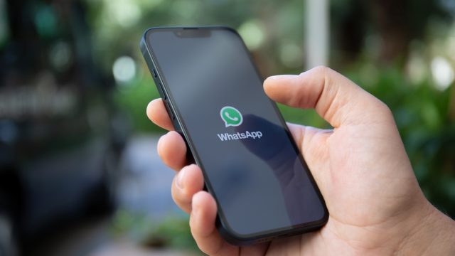 A close up of a phone in someone's hand with the WhatsApp app on the screen