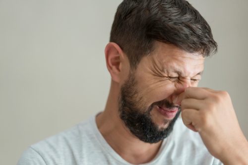 Man pinching nose because of bad smell