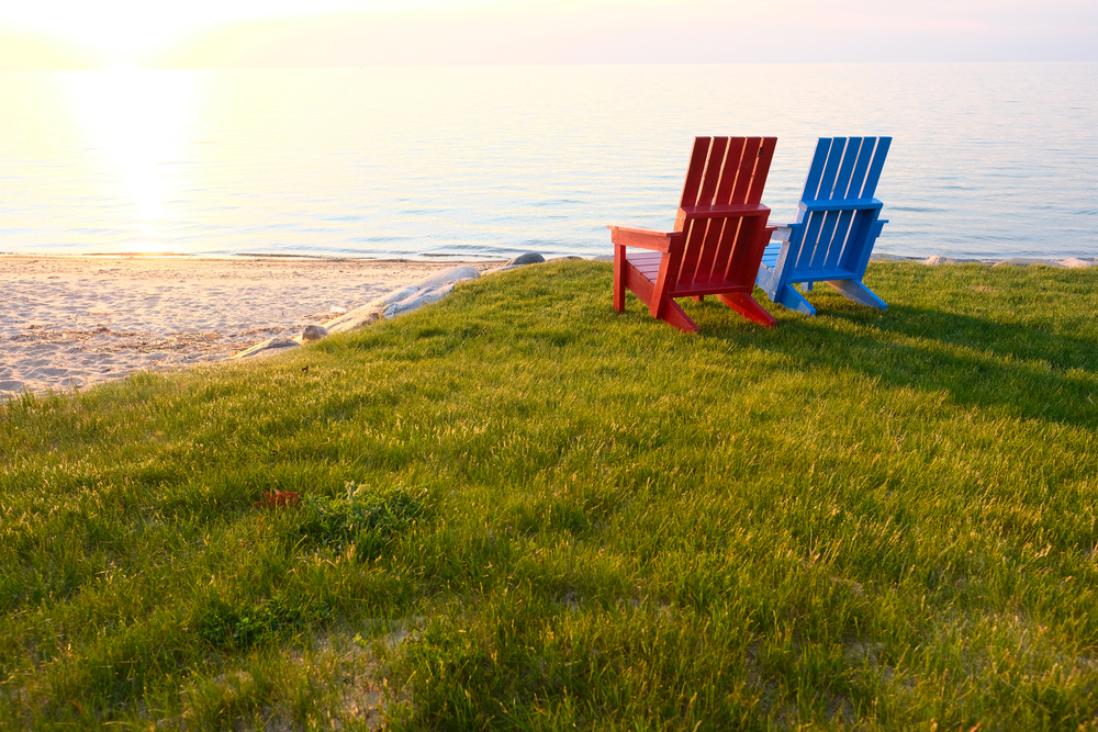 Two chairs on the grass next to a beach on the coast of Lake Huron