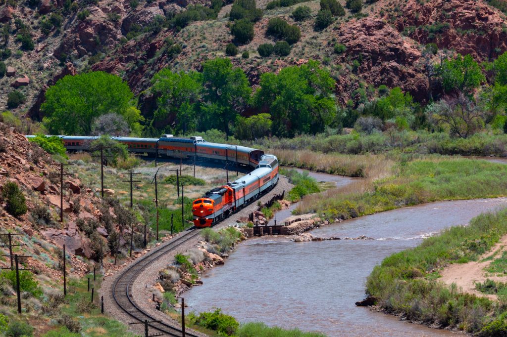 A wide shot of the Royal Gorge Train passing by a river