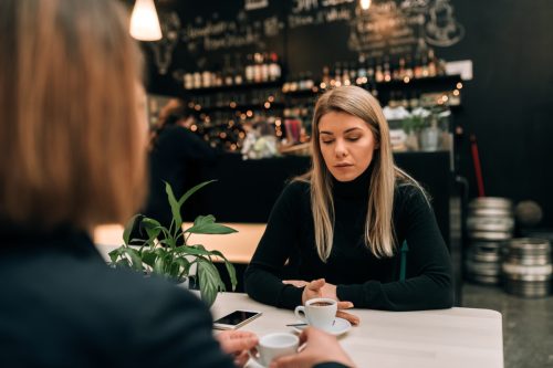 woman looking sad while talking to a friend