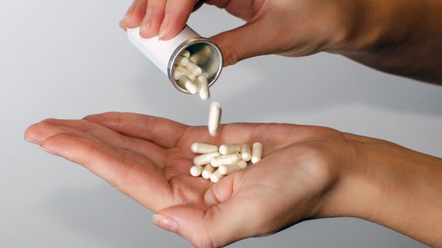 pouring supplements pills into hand